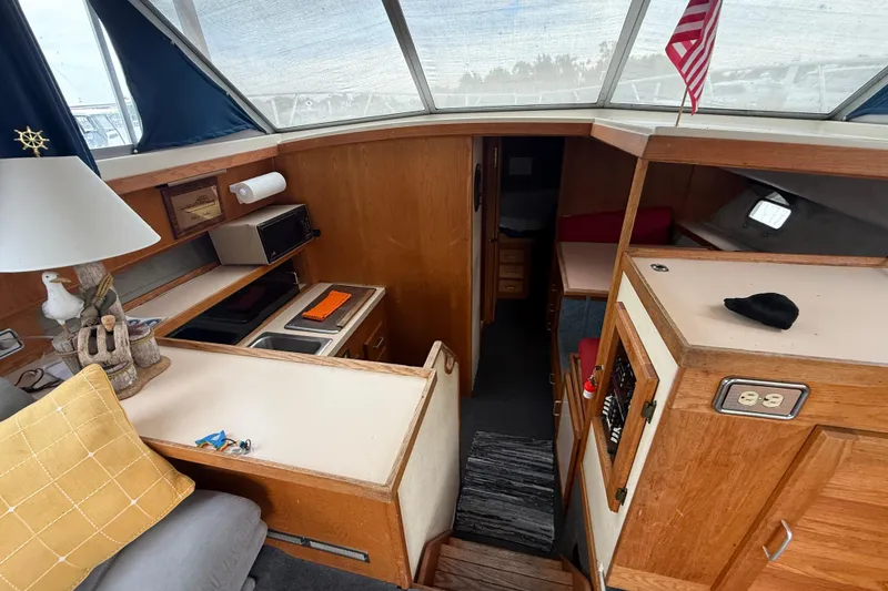 Slide: The Image of 1986 Silverton 34 Convertible interior with kitchenette, seating, and wooden cabinetry. - 13
