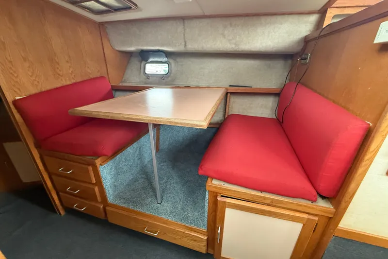 Slide: The Image of 1986 Silverton 34 Convertible interior with red cushioned seating and wooden table. - 21