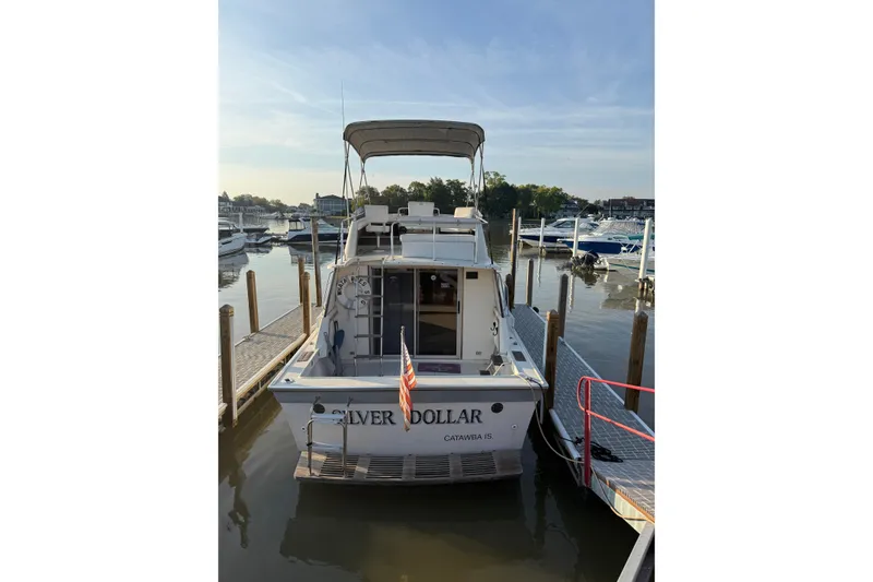 Slide: The Image of 1986 Silverton 34 Convertible boat docked at marina, rear view with American flag. - 25