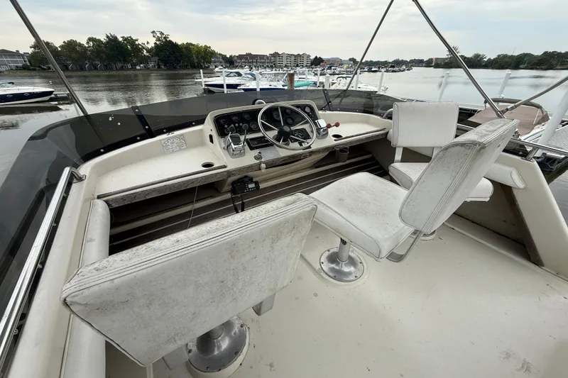 Slide: The Image of 1986 Silverton 34 Convertible boat cockpit with steering wheel and seats, docked by the water. - 8