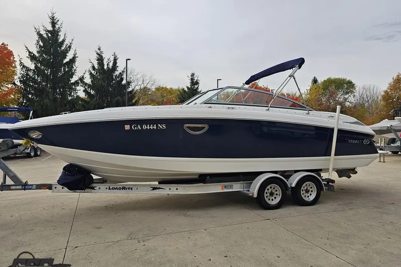 Slide: The Image of 2007 Cobalt 252 boat on trailer, parked outdoors with autumn trees in background. - 19