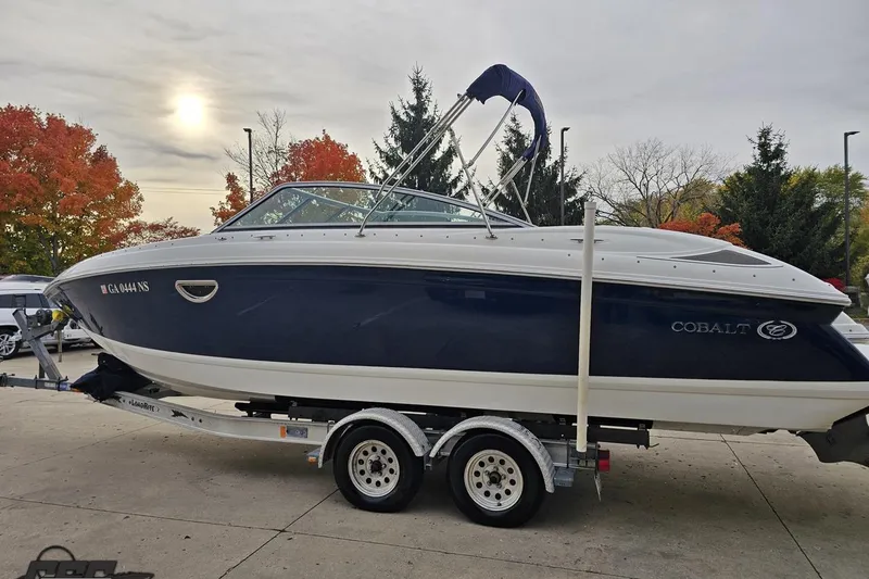 Slide: The Image of 2007 Cobalt 252 boat on trailer, parked outdoors with autumn trees in the background. - 23