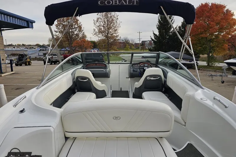 Slide: The Image of 2007 Cobalt 252 boat interior with white seating and steering wheel, docked near autumn trees. - 43