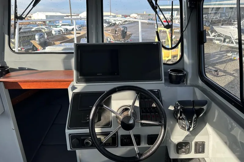 Slide: The Image of Interior helm of 2025 Hewescraft 270 Pacific Explorer with steering wheel and navigation screen. - 6