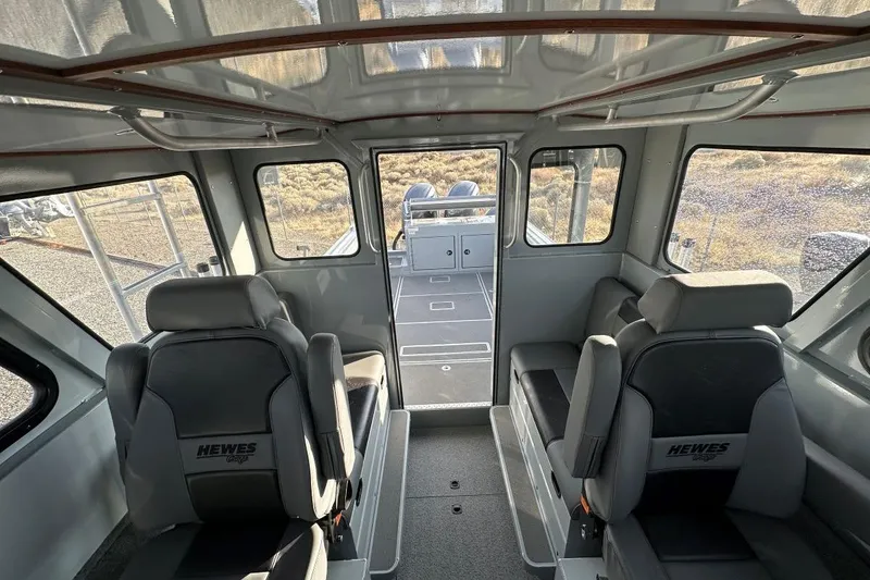 Slide: The Image of Interior of 2025 Hewescraft 270 Pacific Explorer boat, featuring seating and windows. - 9