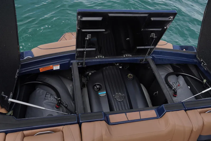 Slide: The Image of 2023 Malibu Wakesetter 23 LSV engine compartment with ballast system, open hatches, and water backdrop. - 14