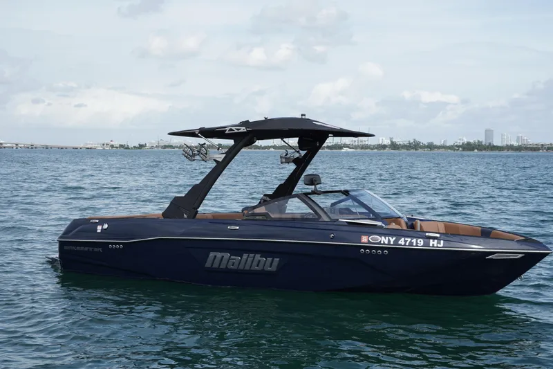 Slide: The Image of 2023 Malibu Wakesetter 23 LSV boat on calm water, city skyline in background. - 18