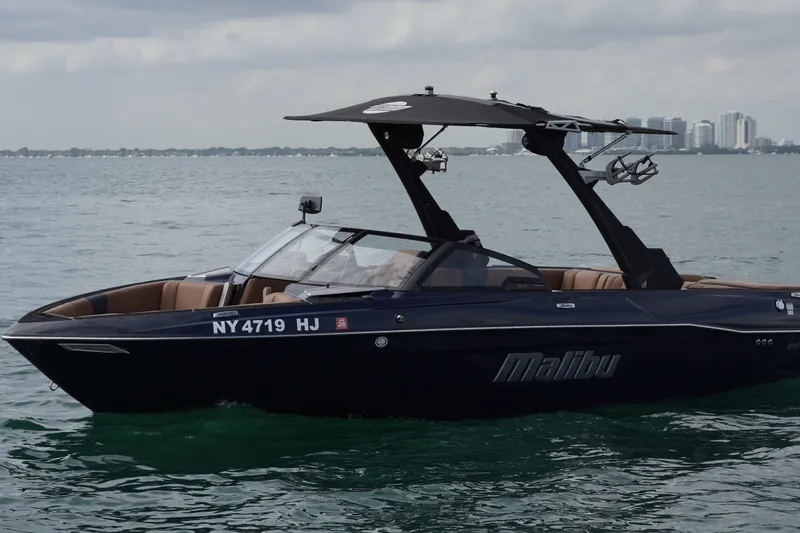 Slide: The Image of 2023 Malibu Wakesetter 23 LSV boat on water, sleek design, city skyline background. - 23