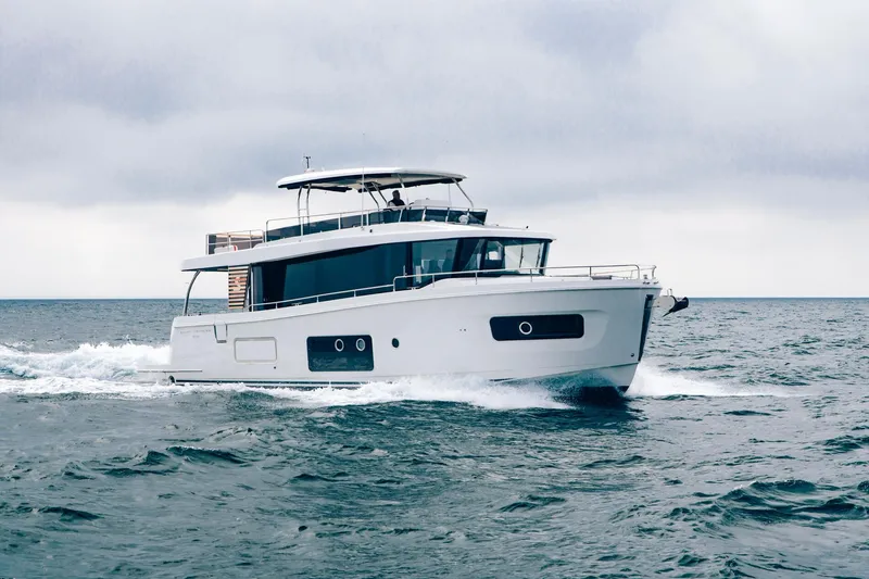 Slide: The Image of 2025 Beneteau Swift Trawler 54 cruising on open water under cloudy skies. - 2