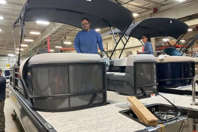 Slide: The Image of 2026 Bennington 22 SSRSE pontoon boat in a factory setting with workers assembling. - 6