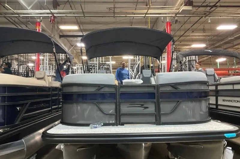 Slide: The Image of 2026 Bennington 22 SSRSE pontoon boat in showroom, featuring sleek design and spacious seating. - 7