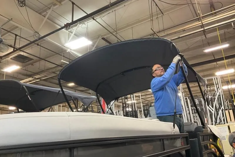 Slide: The Image of Man assembling a 2026 Bennington 22 SSRSE boat canopy in a factory setting. - 8