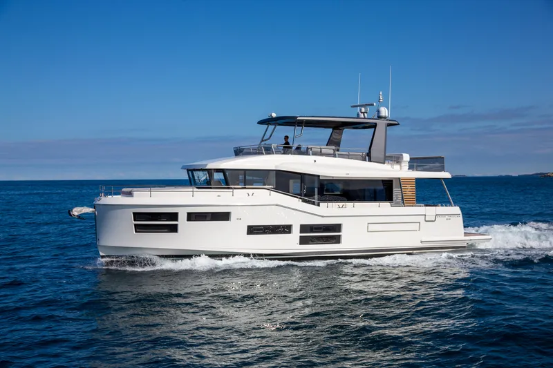 The Image of 2025 Beneteau Grand Trawler 62 cruising on open water under clear blue skies. - 1
