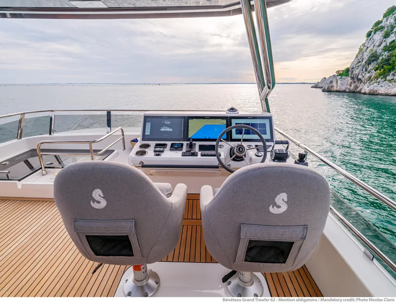 Slide: The Image of 2025 Beneteau Grand Trawler 62 helm with dual seats, overlooking serene ocean view. - 16