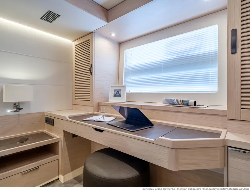 Slide: The Image of Interior of 2025 Beneteau Grand Trawler 62 with modern desk and window. - 26