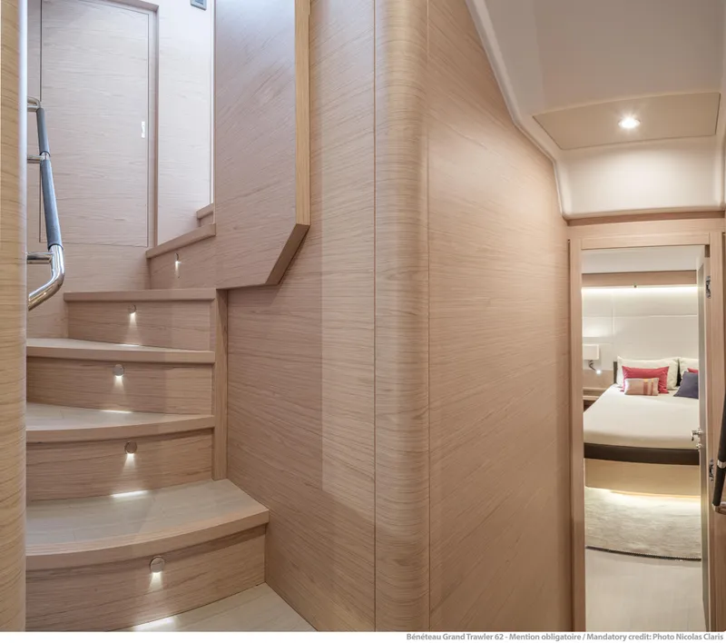 Slide: The Image of Interior of 2025 Beneteau Grand Trawler 62, featuring elegant wooden staircase and cozy bedroom. - 27