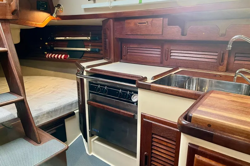 Slide: The Image of Interior of 1994 Pacific Seacraft 31 sailboat, featuring a compact kitchen with wood accents. - 25