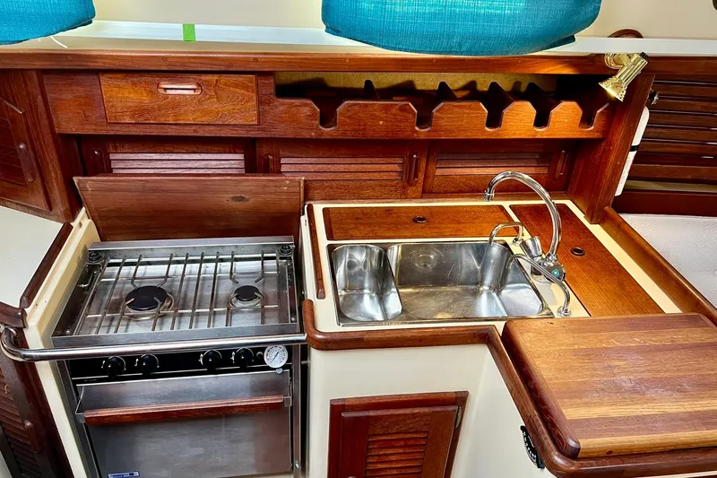 Slide: The Image of Galley kitchen in 1994 Pacific Seacraft 31 sailboat with stove, sink, and wooden cabinetry. - 29