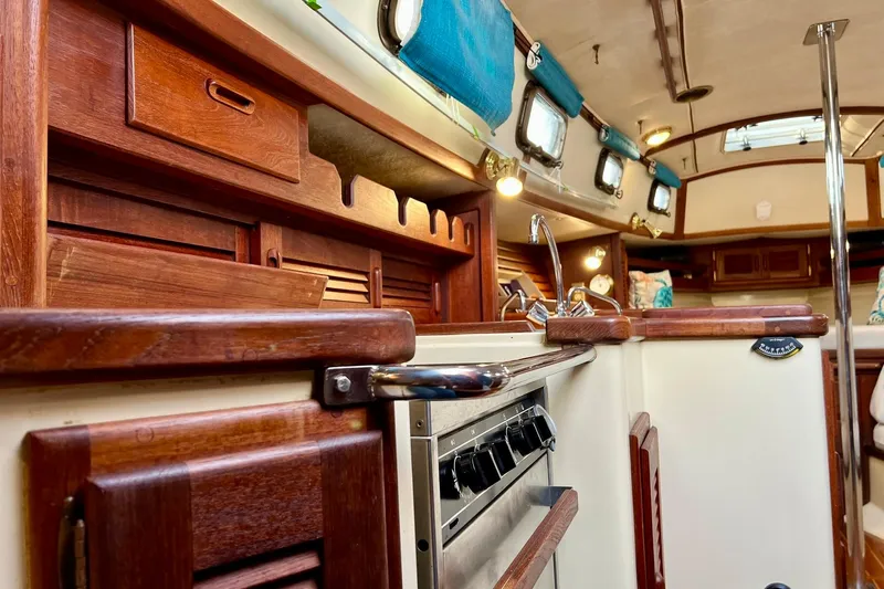 Slide: The Image of Interior of 1994 Pacific Seacraft 31 sailboat with wooden cabinetry and compact kitchen area. - 33