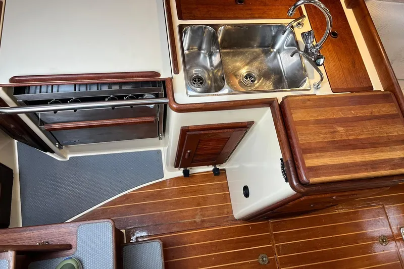 Slide: The Image of Interior of 1994 Pacific Seacraft 31 sailboat, featuring a compact kitchen with wooden cabinetry. - 34