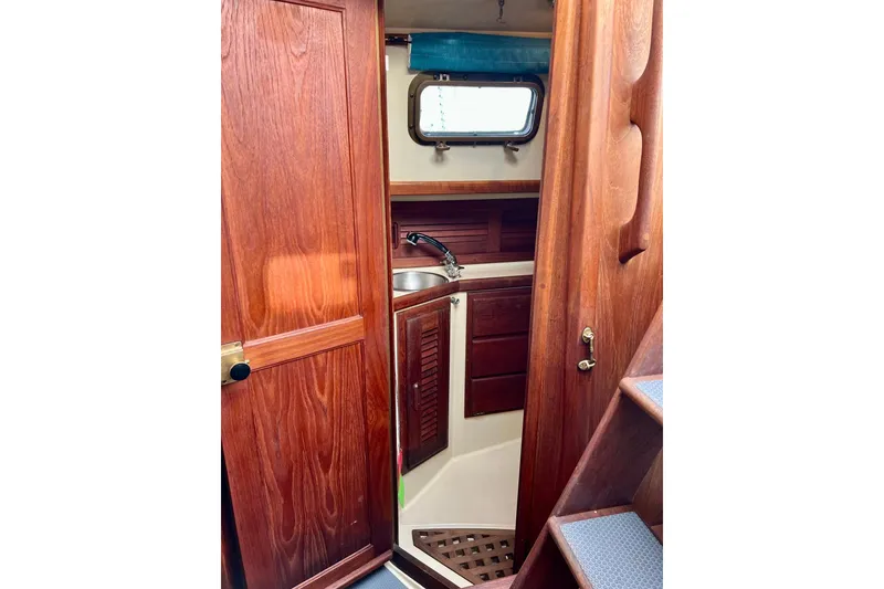 Slide: The Image of Interior of 1994 Pacific Seacraft 31 sailboat, featuring wooden cabinetry and compact sink area. - 36