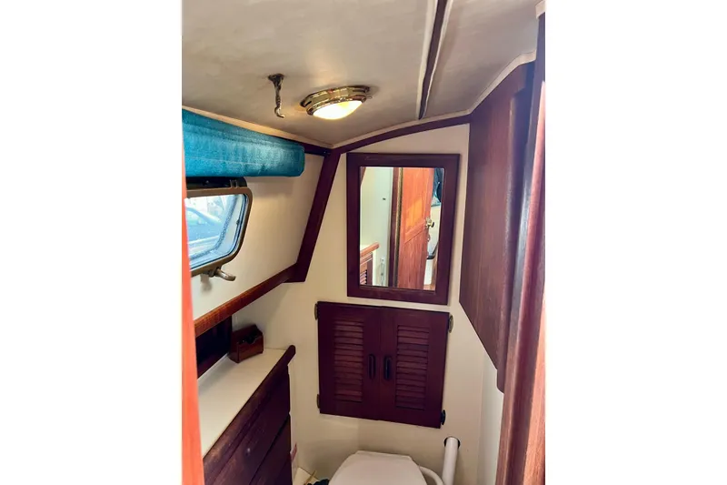 Slide: The Image of 1994 Pacific Seacraft 31 yacht interior bathroom with mirror and wooden cabinets. - 37