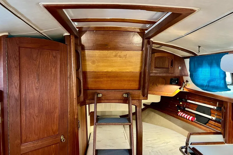 Slide: The Image of Interior of a 1994 Pacific Seacraft 31 sailboat with wooden cabinetry and blue curtains. - 41