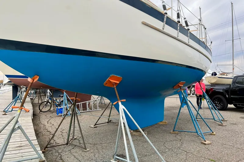 Slide: The Image of 1994 Pacific Seacraft 31 sailboat on stands in a marina, blue hull visible. - 7