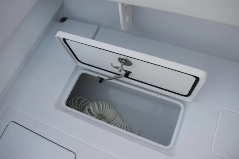 Slide: The Image of Open storage compartment on 2026 Contender 32 ST boat with coiled rope inside. - 31