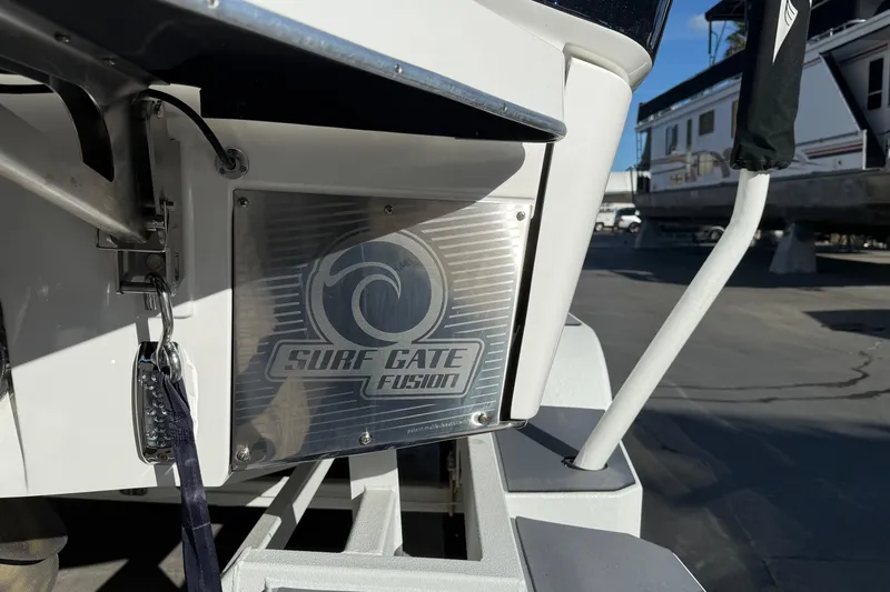 Slide: The Image of 2023 Malibu M240 boat featuring Surf Gate Fusion technology in a marina setting. - 10