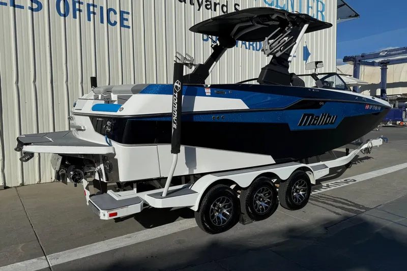 Slide: The Image of 2023 Malibu M240 boat on trailer at dealership, featuring sleek design and modern features. - 12