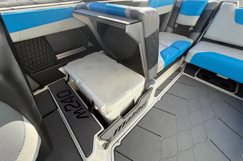 Slide: The Image of 2023 Malibu M240 boat interior with blue and gray seating, featuring a built-in cooler. - 20
