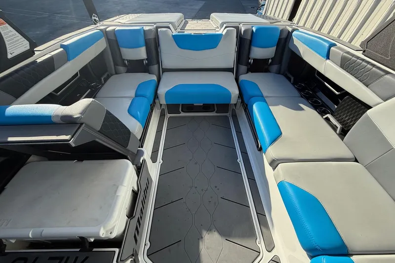Slide: The Image of 2023 Malibu M240 boat interior with blue and gray seating, spacious layout. - 22