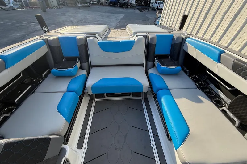 Slide: The Image of 2023 Malibu M240 boat interior with blue and gray seating, featuring cup holders and storage. - 23