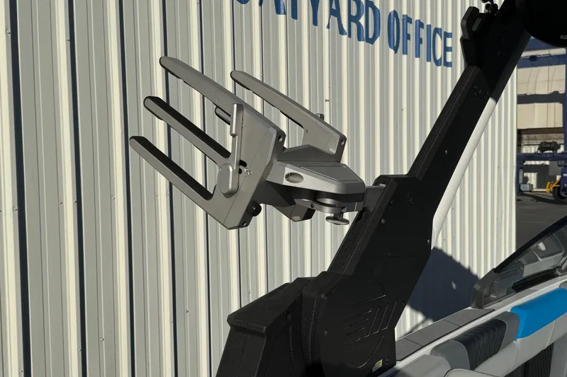 Slide: The Image of 2023 Malibu M240 boat with a sleek wakeboard rack against a metal wall. - 29