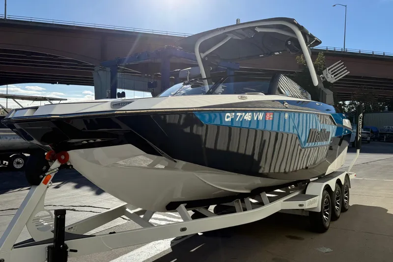 Slide: The Image of 2023 Malibu M240 boat on trailer under bridge, showcasing sleek design and modern features. - 7