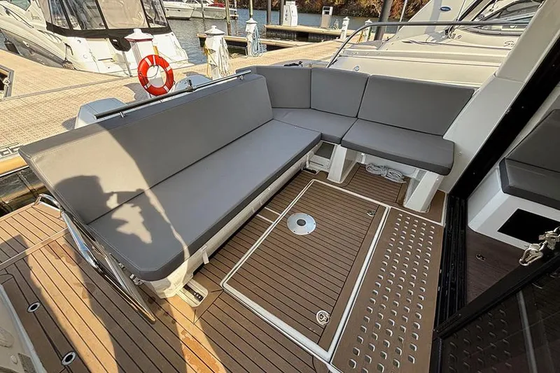 Slide: The Image of 2023 Beneteau Antares 11 boat deck with gray seating and wooden flooring. - 10