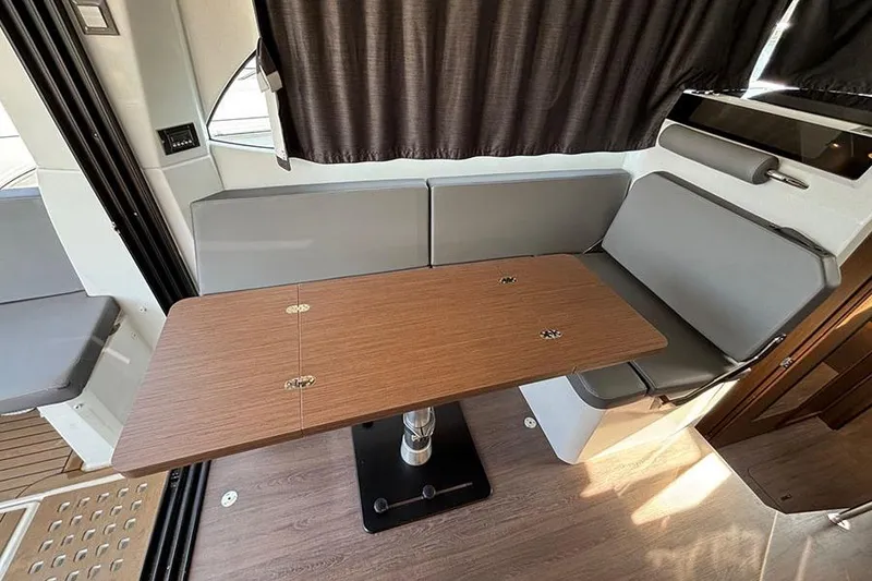 Slide: The Image of Interior of 2023 Beneteau Antares 11, featuring a wooden table and gray seating. - 13