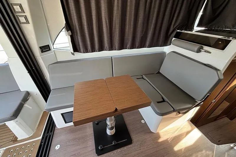 Slide: The Image of Interior of 2023 Beneteau Antares 11 with gray seating and wooden table. - 14