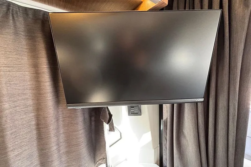 Slide: The Image of Flat-screen TV inside 2023 Beneteau Antares 11, surrounded by dark curtains. - 18