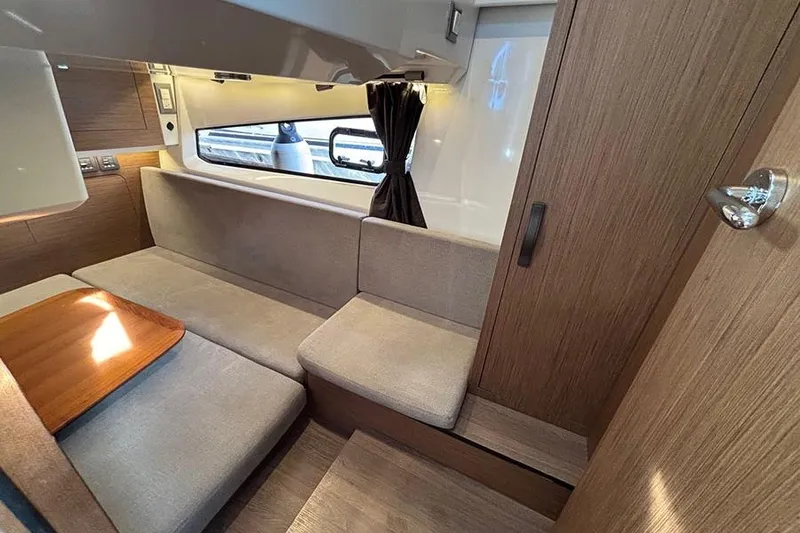 Slide: The Image of Interior of 2023 Beneteau Antares 11, featuring cozy seating and wooden accents. - 29