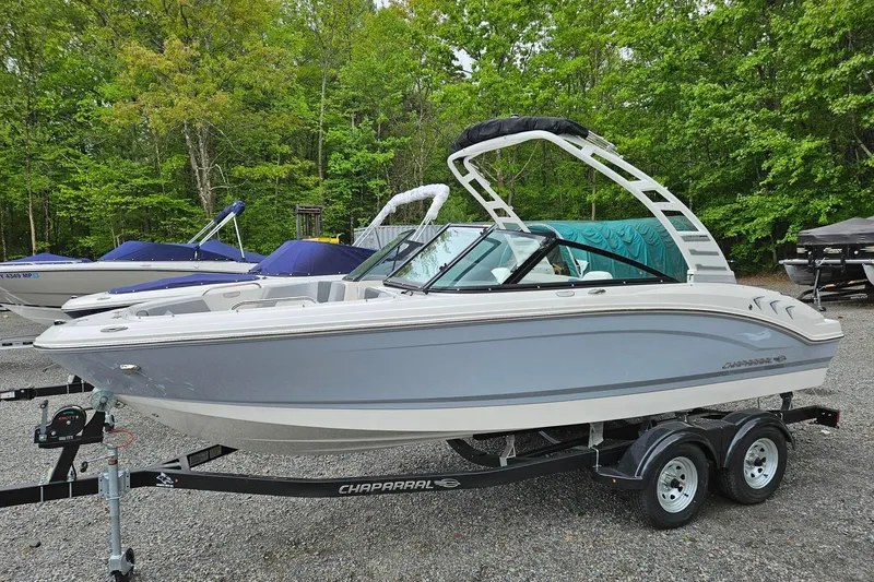 The Image of 2025 Chaparral 21 SSi boat on trailer, surrounded by trees and other boats. - 0