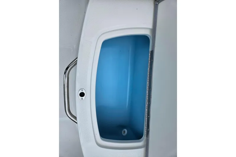 Slide: The Image of 2025 Chaparral 21 SSi boat storage compartment with blue interior and stainless steel handle. - 2