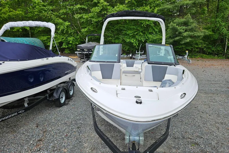 Slide: The Image of 2025 Chaparral 21 SSi boat on trailer, parked outdoors with trees in background. - 5