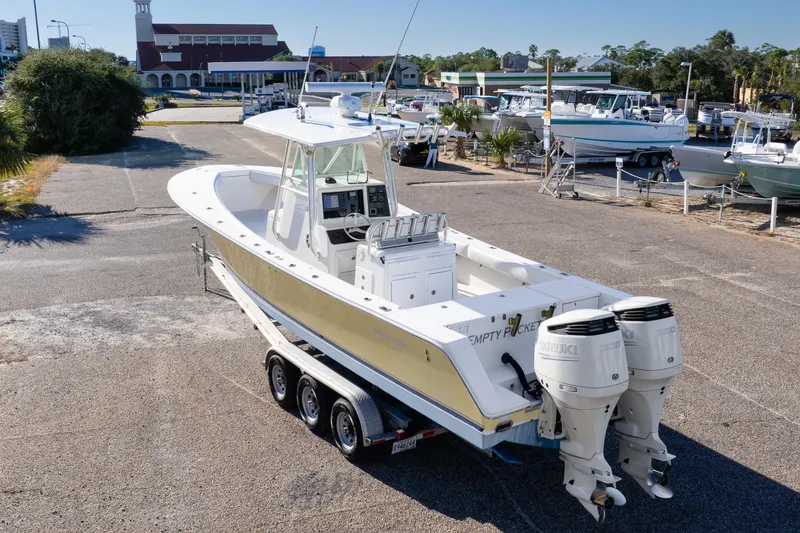 Slide: The Image of 2005 Regulator 32 Classic boat on trailer with twin Suzuki engines in a marina setting. - 12