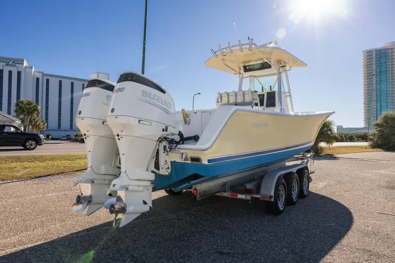 Slide: The Image of 2005 Regulator 32 Classic boat with twin Suzuki engines on a trailer, sunny day. - 14