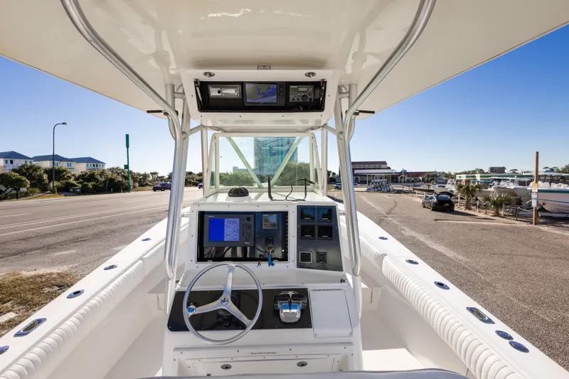 Slide: The Image of 2005 Regulator 32 Classic boat cockpit with navigation equipment and steering wheel, docked near a marina. - 19