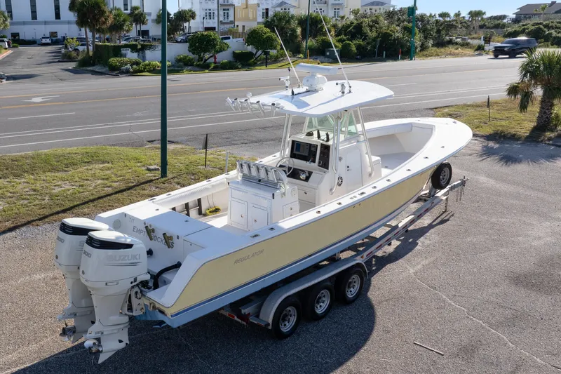 Slide: The Image of 2005 Regulator 32 Classic boat on trailer with dual Suzuki engines, parked near a road. - 2