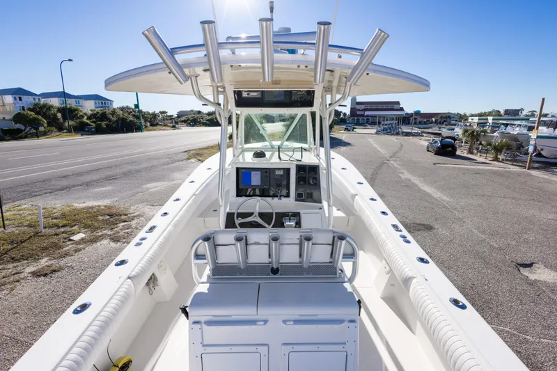 Slide: The Image of 2005 Regulator 32 Classic boat with center console and rod holders, parked near a marina. - 22