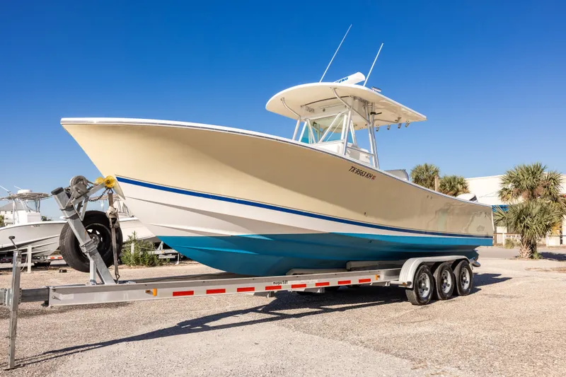 Slide: The Image of 2005 Regulator 32 Classic boat on trailer, parked outdoors under clear blue sky. - 6